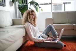 woman with laptop sitting next to couch